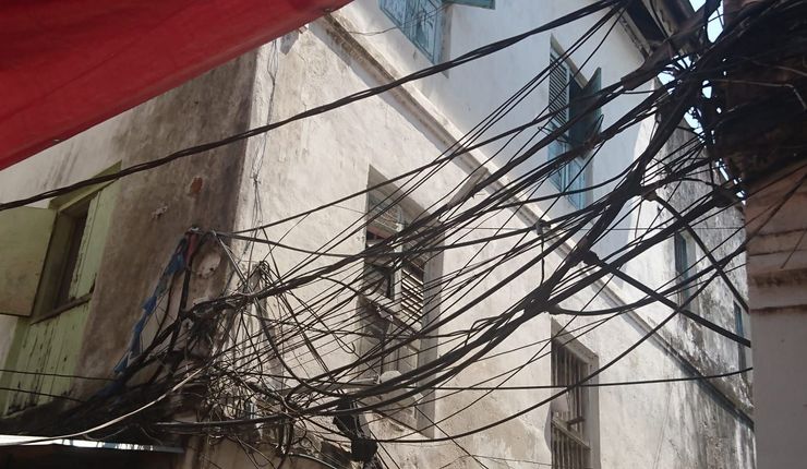 Bundles of electrical wires, assorted cables and water pipes attached to houses throughout the Stone Town Zanzibar.