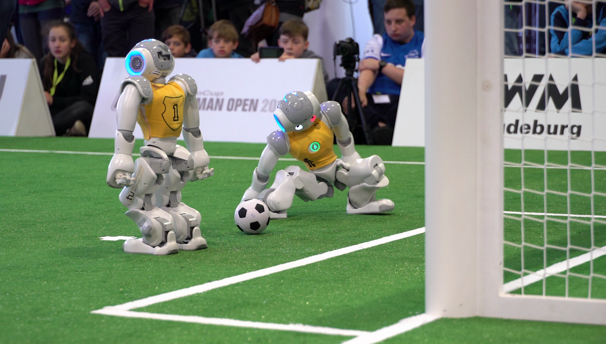 zur Vergrößerungsansicht des Bildes: Filmszene zwei kleine Roboter spielen Fußball
