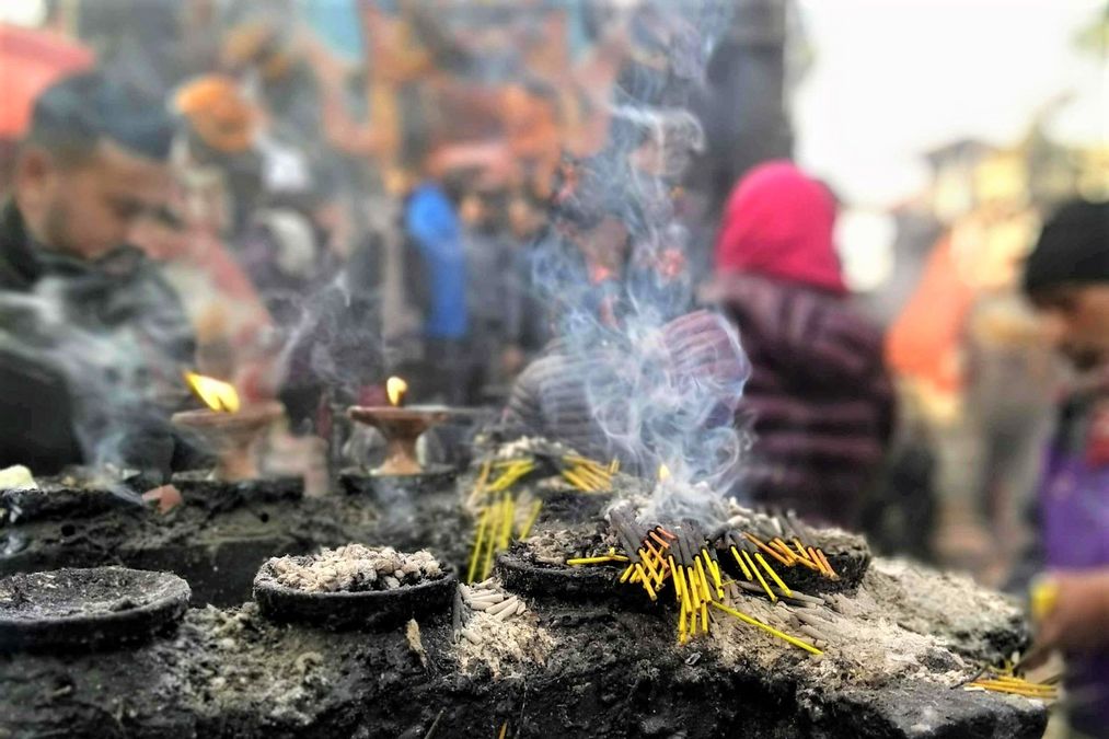 enlarge the image: Räucherwerk brennt auf einem Stein, im Hintergrund stehen Menschen darum