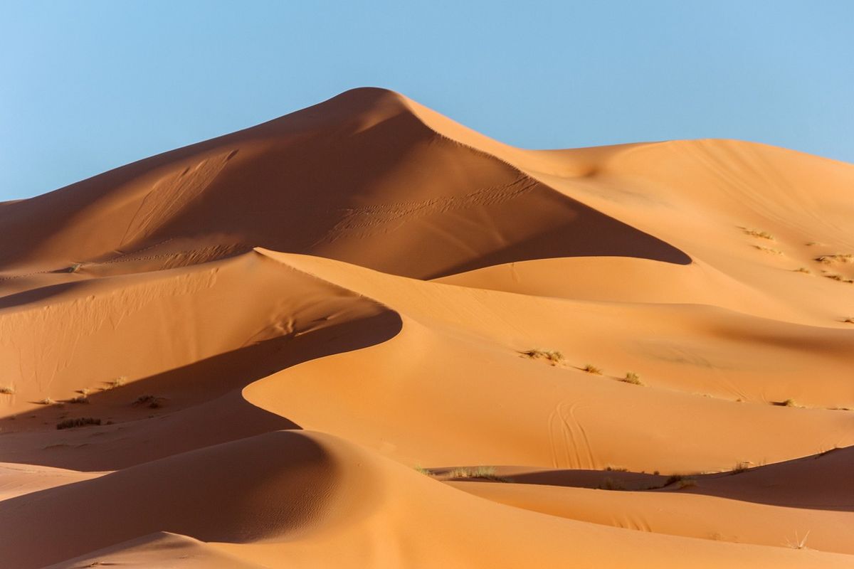 zur Vergrößerungsansicht des Bildes: Das Stock-Foto zeigt eine Landschaft mit goldenen Sanddünen und blauem Himmel in der Wüste Sahara